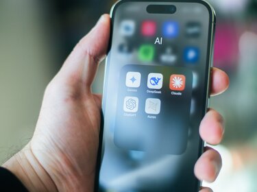 Neue KI-Kennzeichnungen: Inhalte besser erkennen und einordnen In der Hand hält jemand ein Handy. Auf dem Bildschirm ist ein Ordner geöffnet in dem sich verschiedene KI-Apps befinden. Beispielsweise Claude oder Chatgpt.