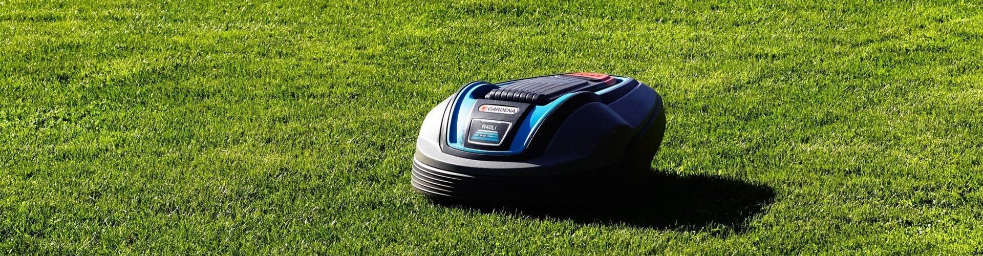 Tipps für die Gartenarbeit mit smarter Technologie kleiner, schwarzer Rasenmäher-Roboter fährt über grünen Rasen