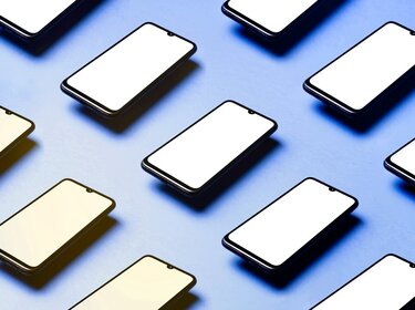 Diverse Smartphones liegen parallel nebeneinander angeordnet auf einem blauen Untergrund