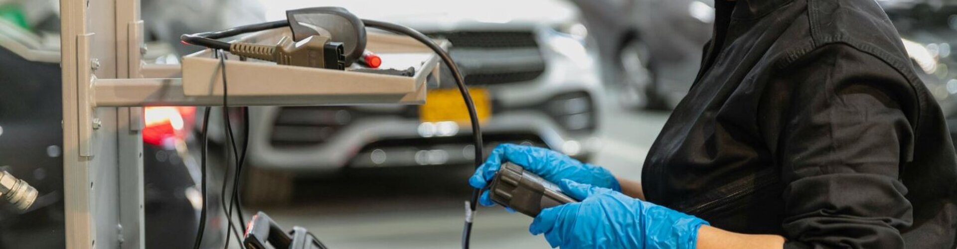 Eine Mechanikerin steht in einer Autowerkstatt an einem Laptop
