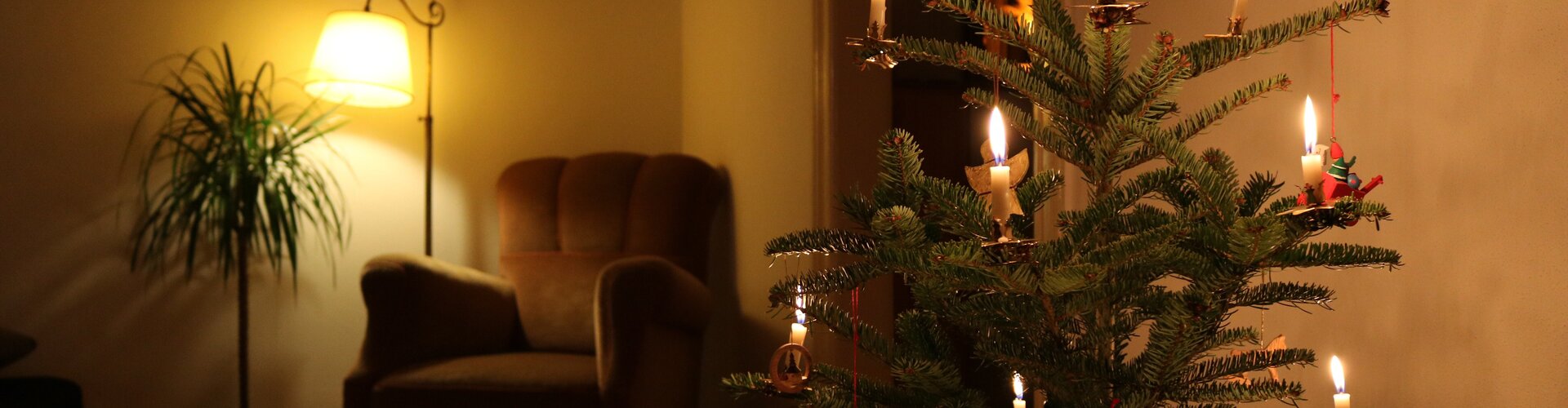 Brennende Kerzen an Weihnachtsbaum im Wohnzimmer