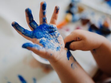 TÜV-Verband: Fingermalfarben können Gesundheit schädigen Kinderhand mit blauer Fingermalfarbe