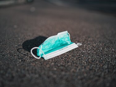 TÜV-Unternehmen stellen Grundversorgung sicher Eine Hygieneschutzmaske liegt auf Asphalt