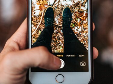 So schützen Handy-Nutzer:innen den Akku vor Frost und Kälte Mann man ein Foto der eigenen Beine und Füße mit dem Smartphone
