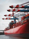 Rotes großes Containerschiff liegt an einem Hafen