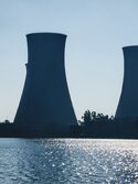 Drei Kühltürme von Kernreaktoren mit einem See im Vordergrund