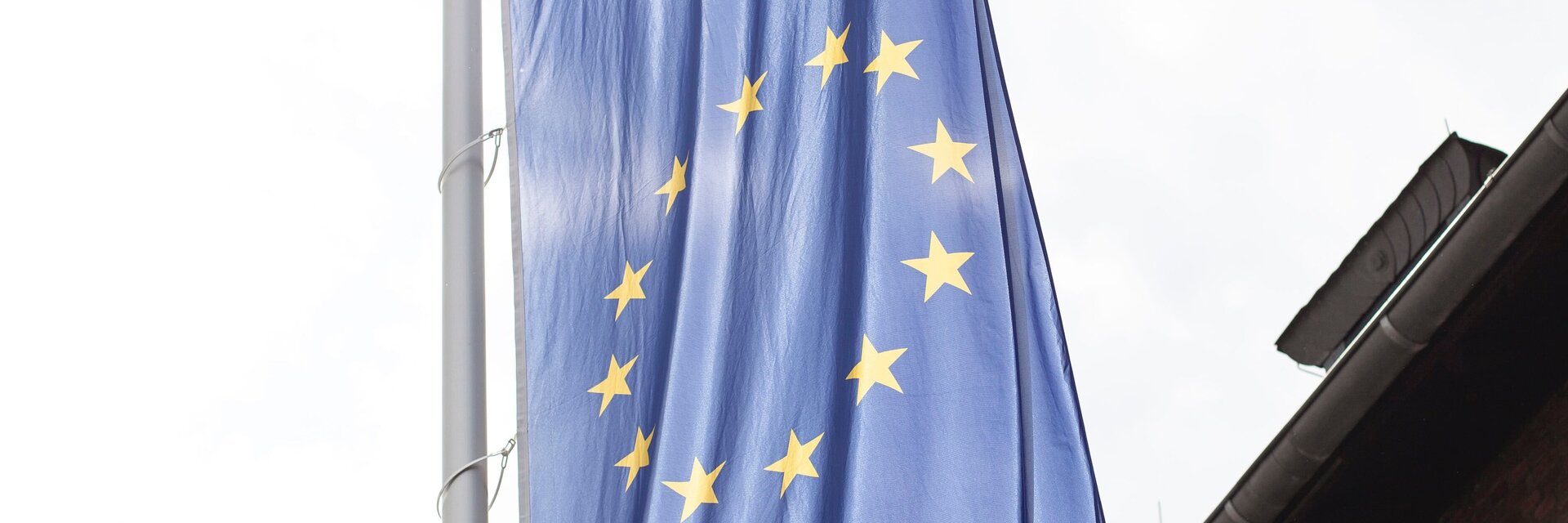 Eine Europafahne mit den goldenen Sternen weht vor einem Backsteingebäude