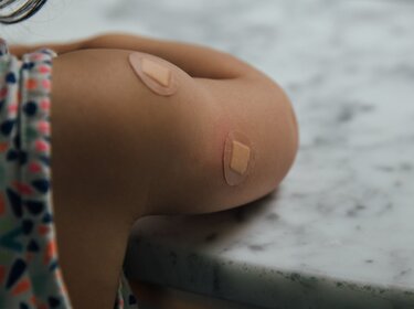 Schutz vor Covid-19: TÜV-Verband fordert nationale Impfstrategie Auf einem Kinderoberarm sind Pflaster von einer Impfung zu sehen
