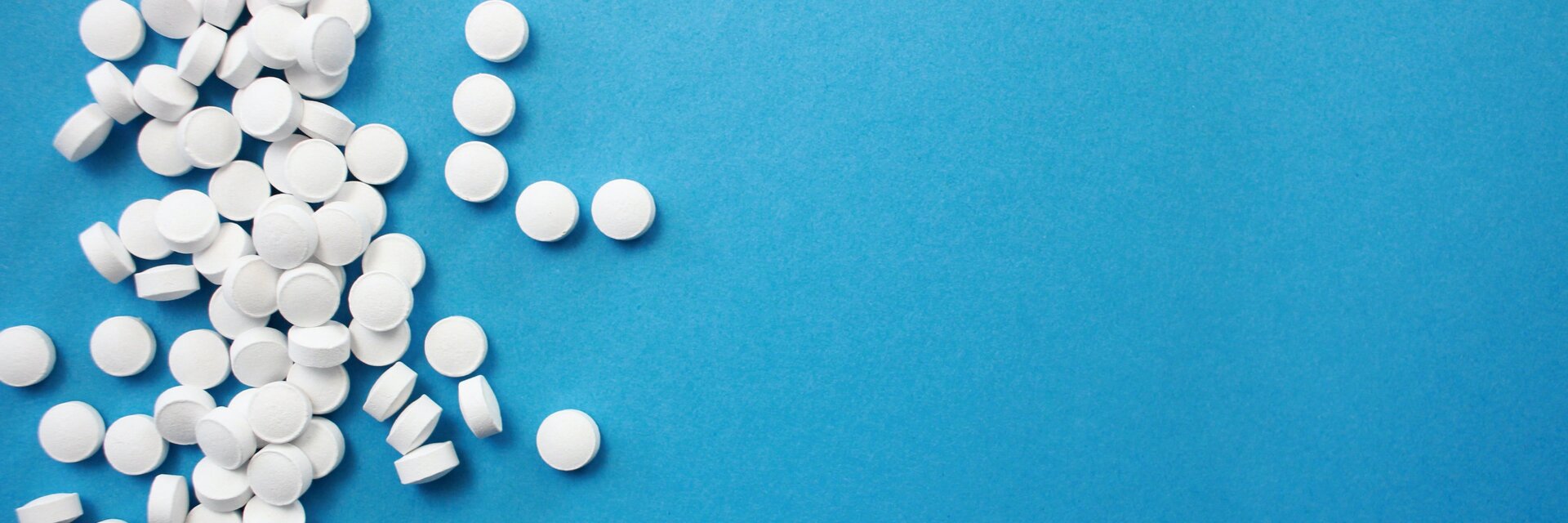 Ein Haufen weißer Tabletten liegt auf einem blauen Untergrund