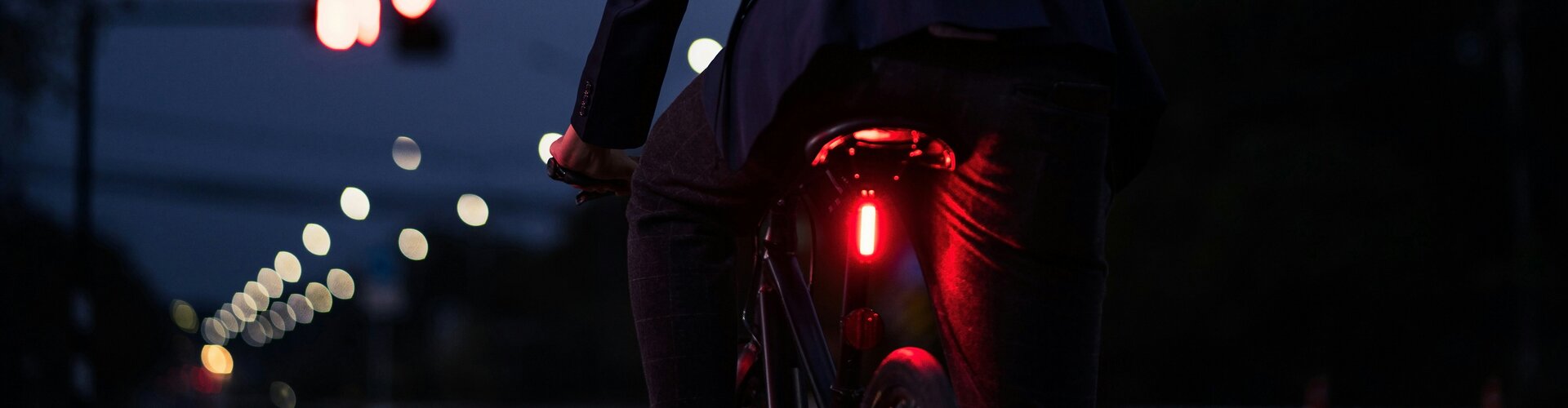 Intelligente Fahrrad-Gadgets: Was Radfahren sicherer macht Ein Fahrradfahrer bei Nacht. Zu sehen von hinten. Er Trägt einen Helm und ein rotes Licht ist m Fahrr