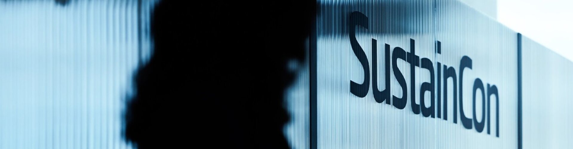 Silhouette einer Speakerin vor der Bühnenwand der SustainCon 2025