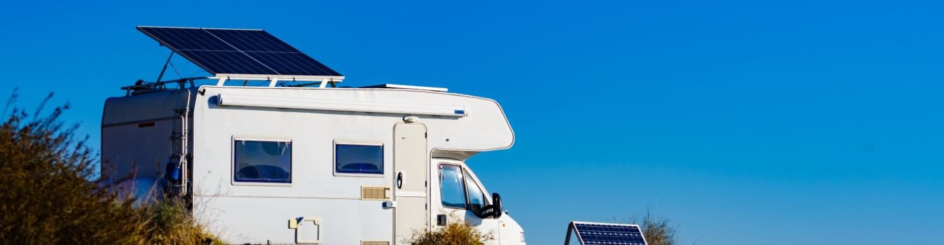 Ein weißes Wohnmobil mit PV-Anlage auf dem Dach steht in steiniger Umgebung