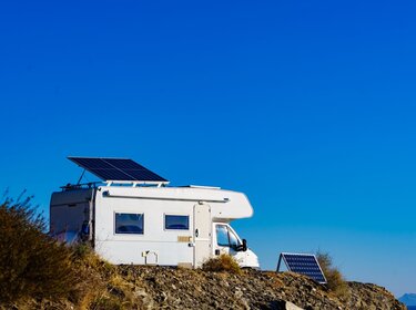 Ein weißes Wohnmobil mit PV-Anlage auf dem Dach steht in steiniger Umgebung