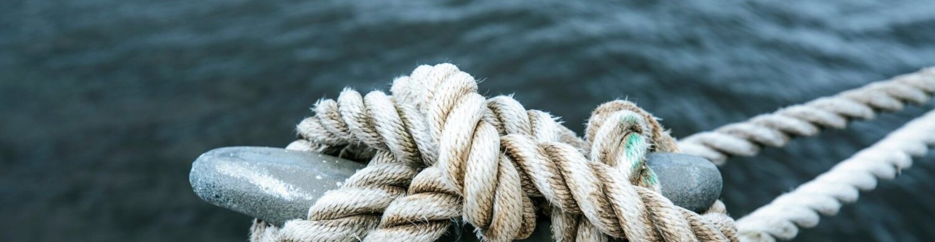Ein Tau ist am Hafen fest verknotet